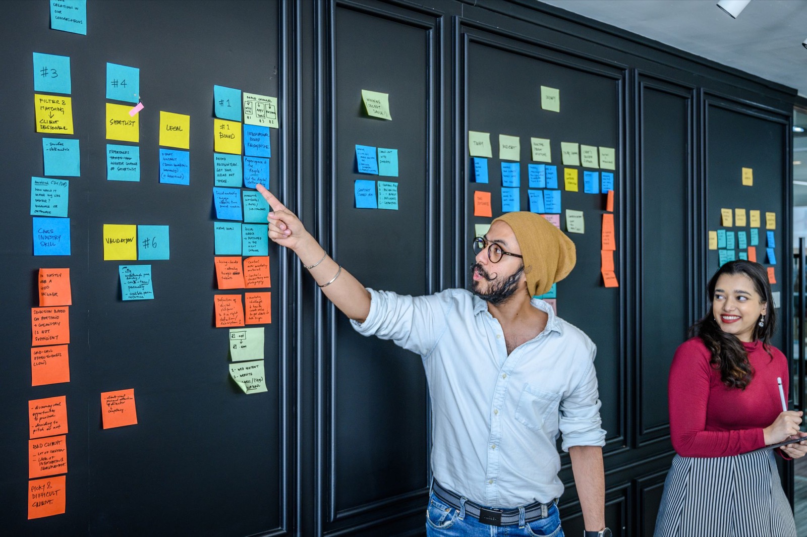 A colleague pointing at columns of notes on a wall board